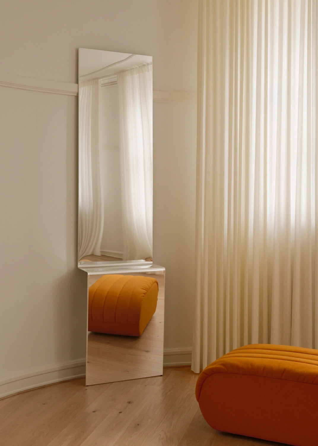 Specchio Pleat MUUTO ambientato con pouf arancione